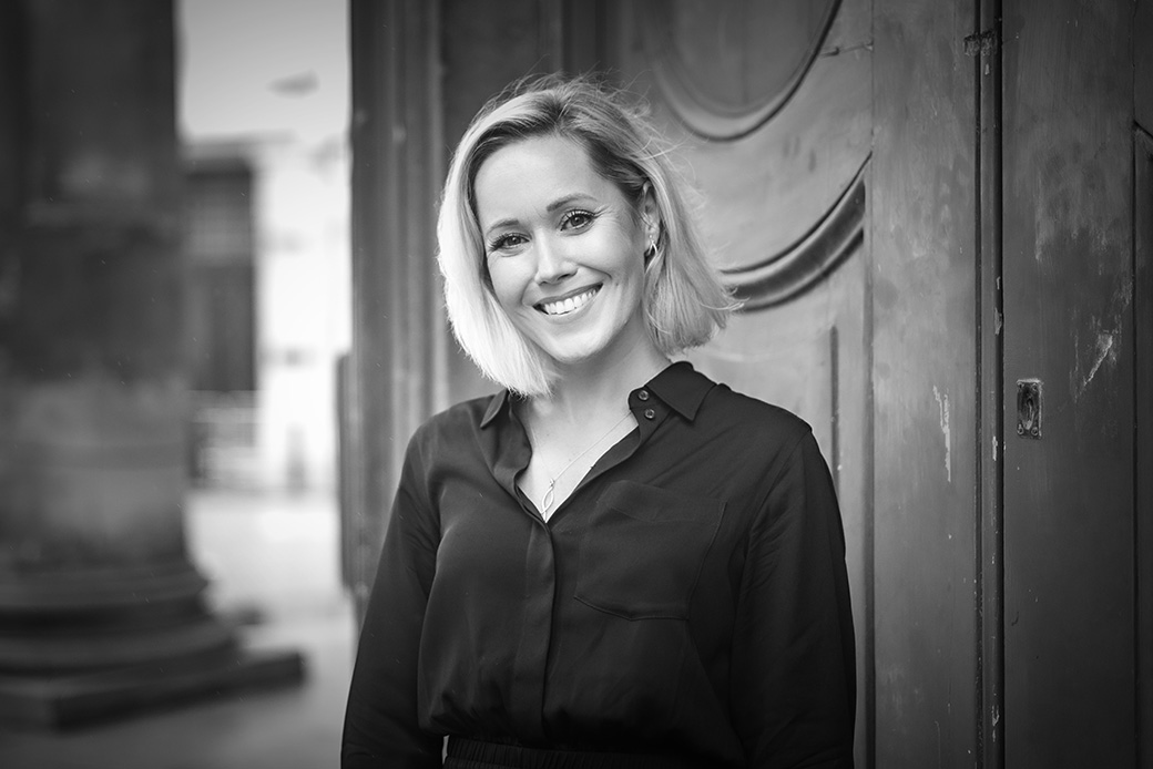 Black and white professional headshot of a smiling woman in smart attire
