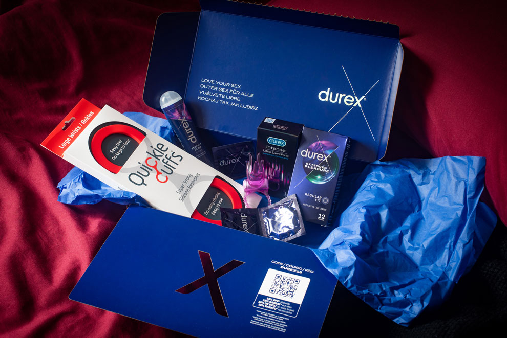Open Durex gift box placed on a red bed sheet