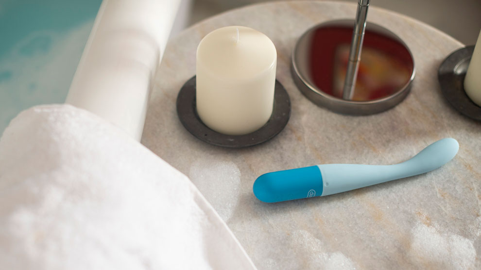 Blue massager on a marble table beside a bath tub
