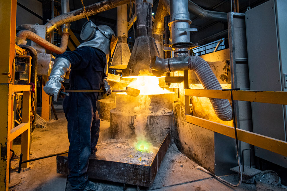 Metal worker lifting molten metal from a furnace
