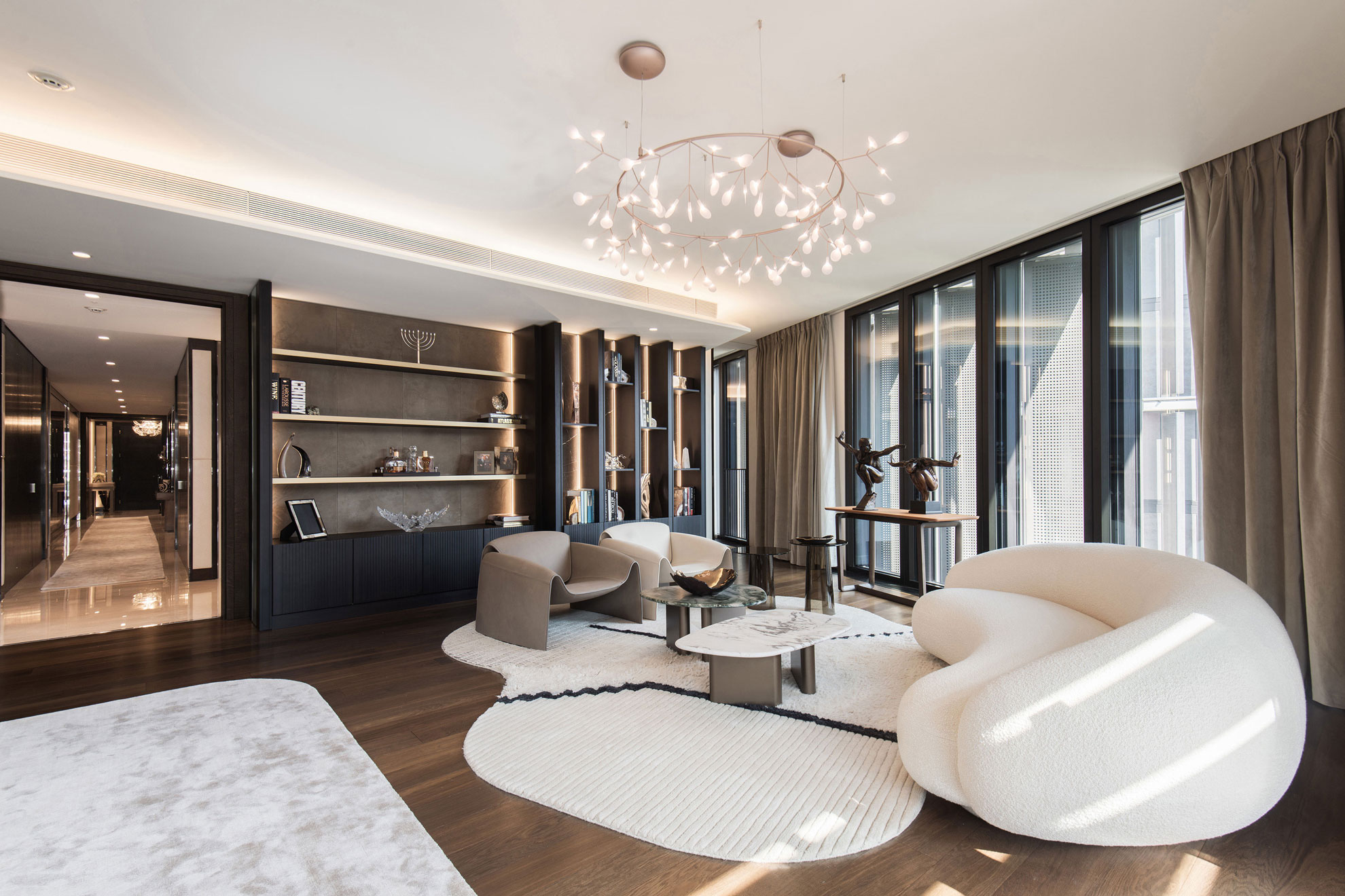 Living area in a high-end, prestigious apartment, with full height windows, designer sofas and feature lighting