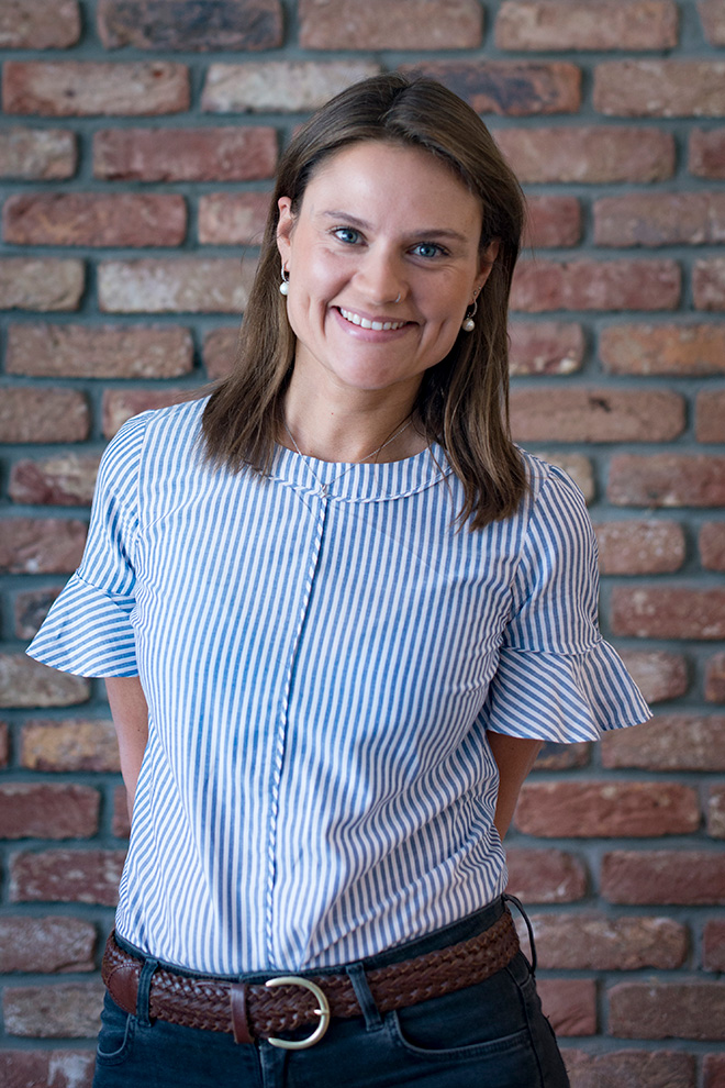 Smiling female professional in patterned blouse, standing in office environment