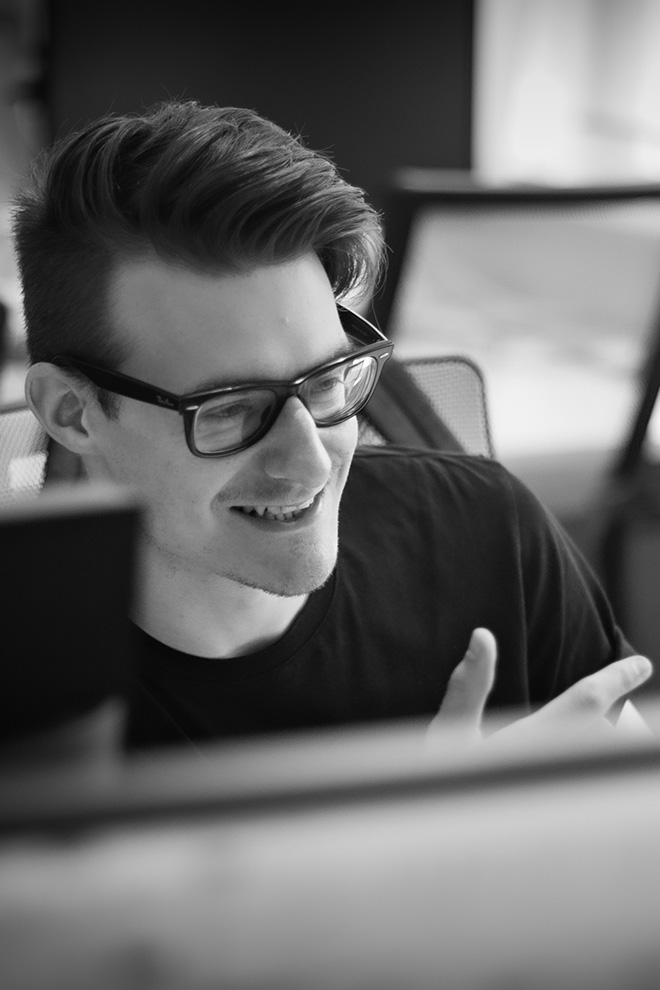 Informal, candid shot of a young male office worker in conversation with someone out of shot