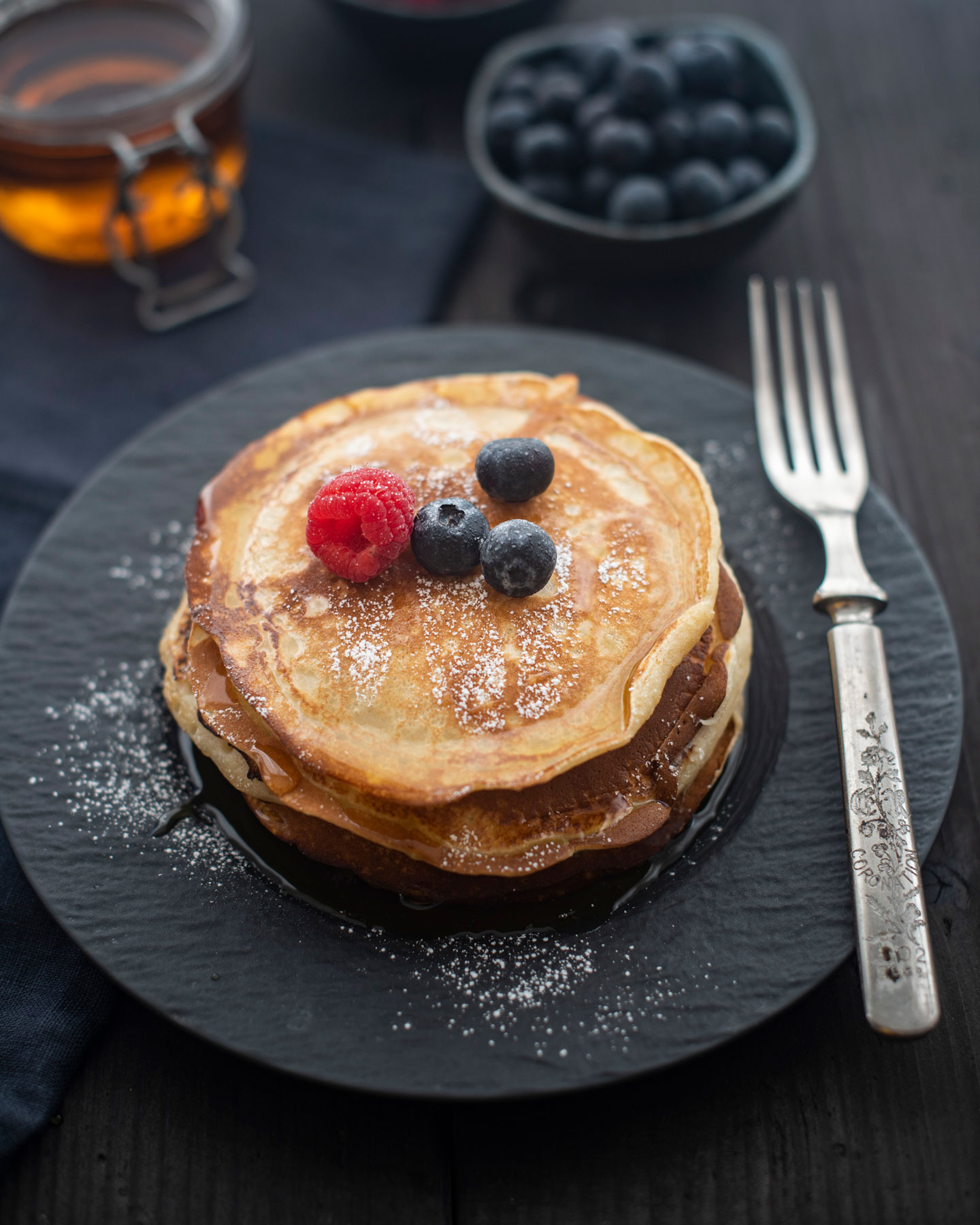 Stack of golden pancakes with fresh berries and syrup, styled for a breakfast food photoshoot