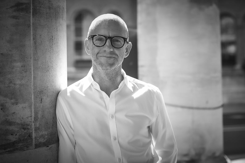 Black and white business portrait of a man with glasses, outdoor professional headshot
