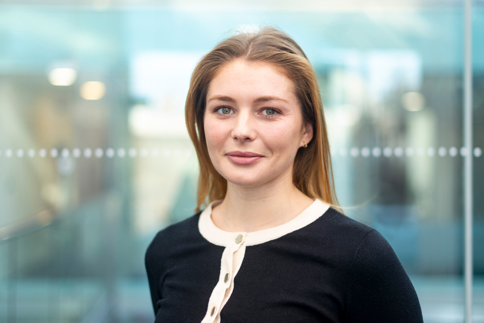 Young professional woman in modern office, corporate headshot with natural expression
