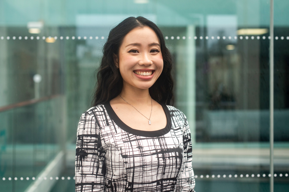 Smiling female professional in patterned blouse, standing in office environment
