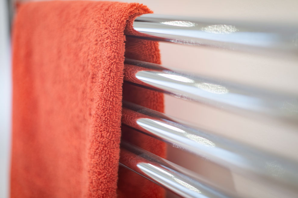 Close up of an orange towel of a stylish bathroom radiator