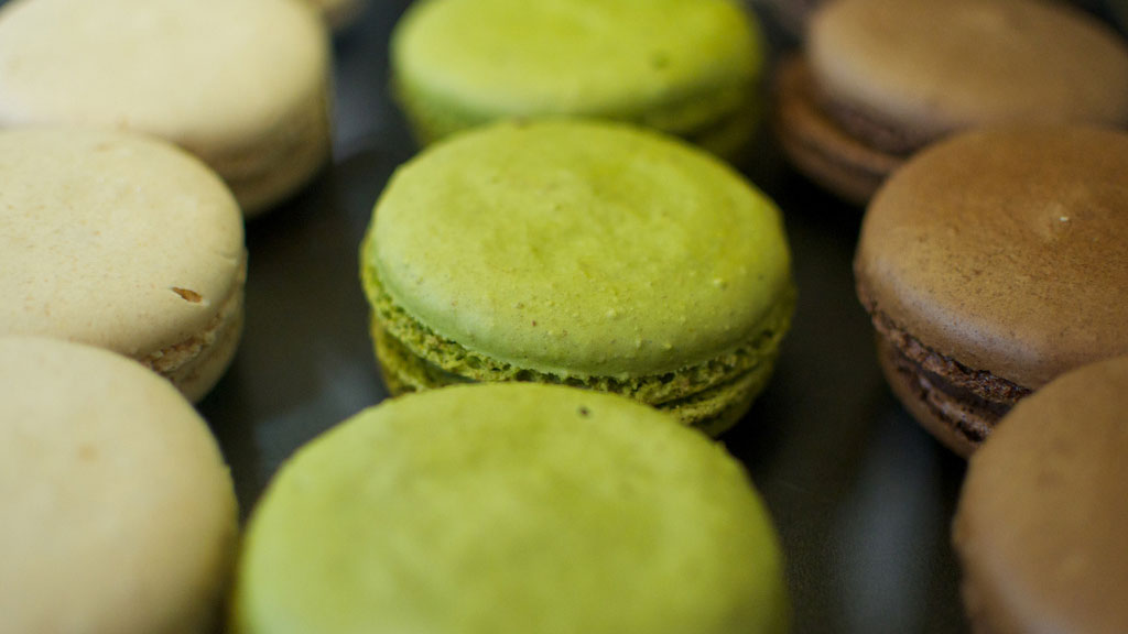 Assorted colourful macarons in green, yellow, and chocolate brown, ideal for dessert photography