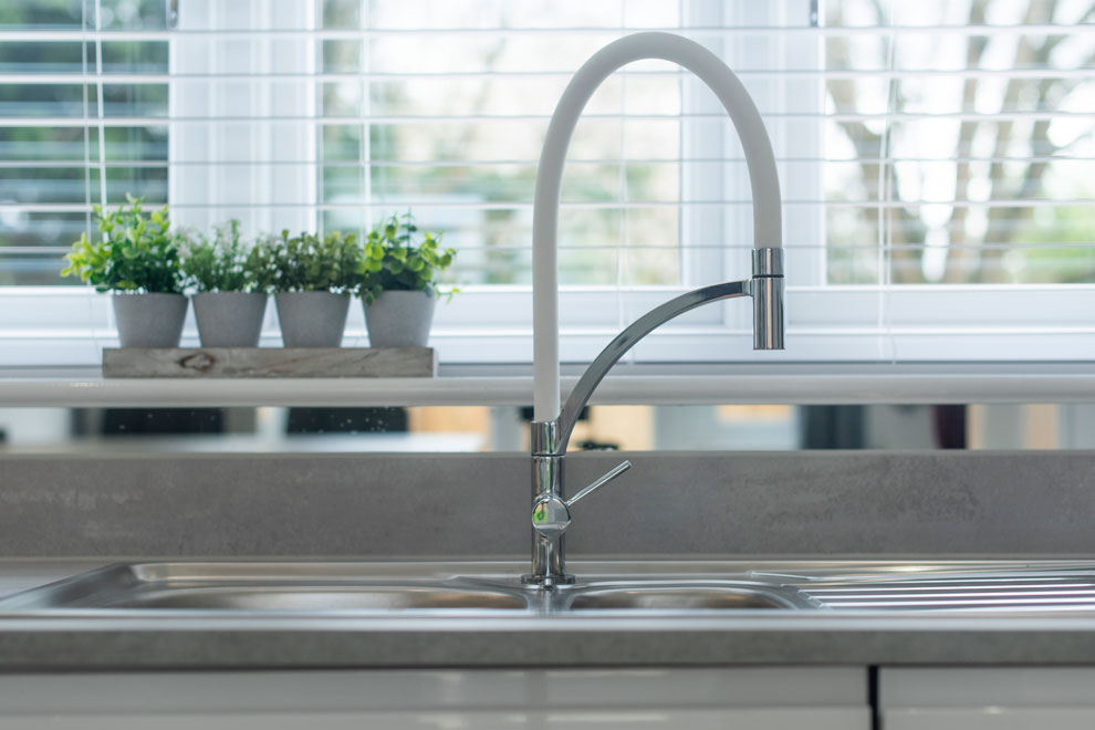 Close up of a stylish curved tap in a contemporary kitchen.