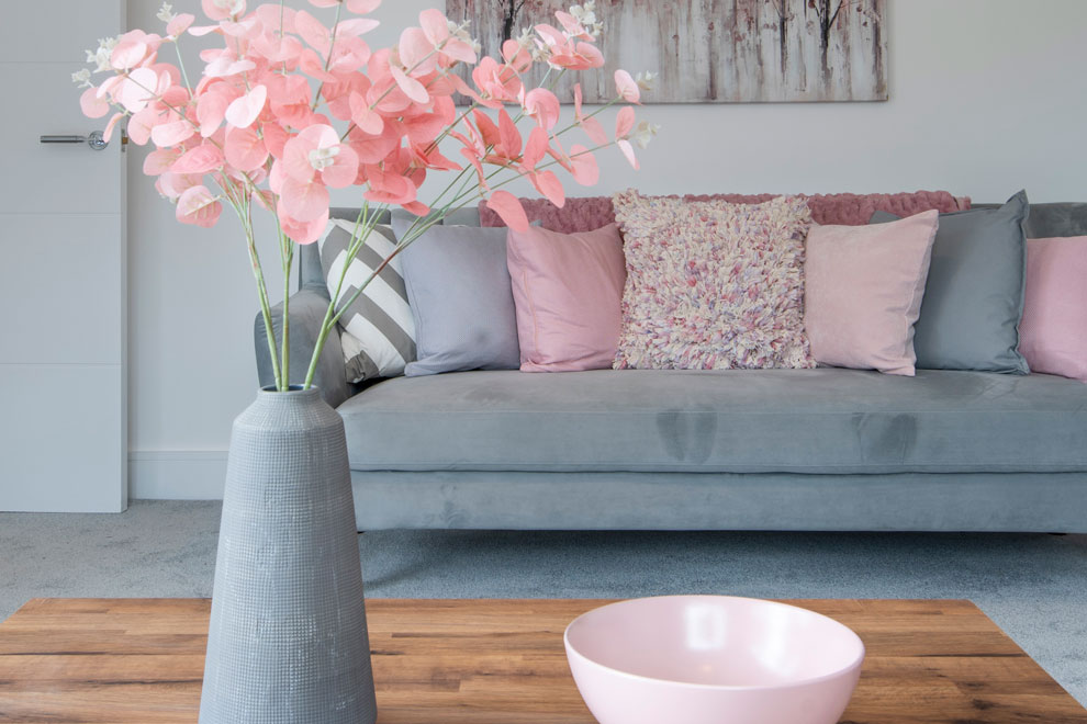 Pink flowers in a grey vase in a cool, neutral living room