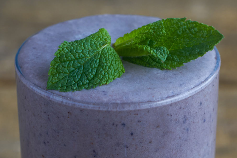 Blueberry smoothie in a glass, garnished with mint leaves