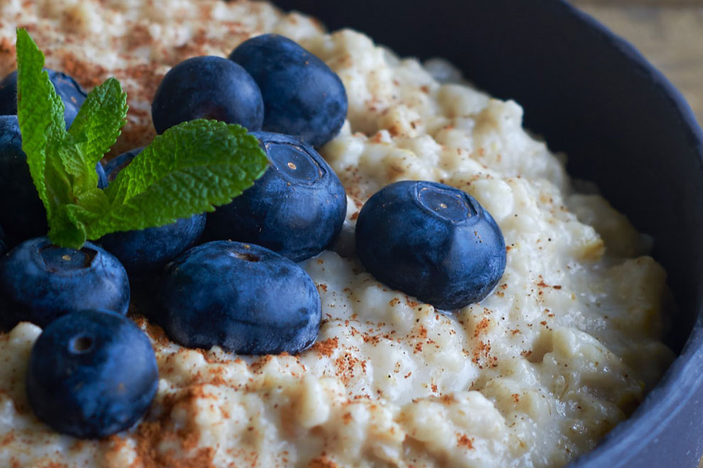 Creamy porridge topped with blueberries and fresh mint leaves, styled for a breakfast shoot