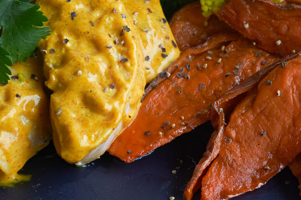 Chicken curry in a creamy yellow sauce with roasted vegetables, plated for food photography portfolio