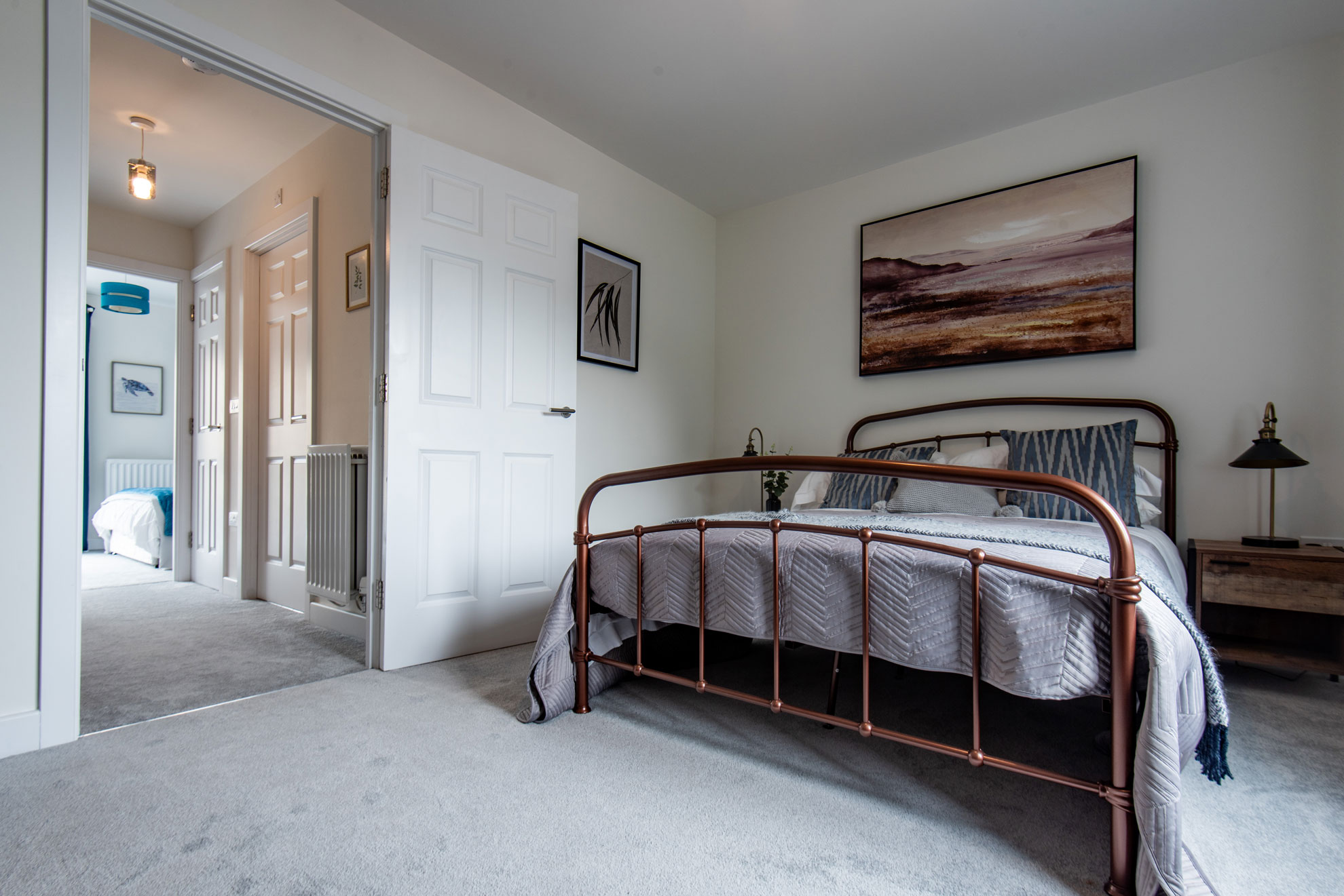 Modern bedroom with neutral colours and a view down a hallway.