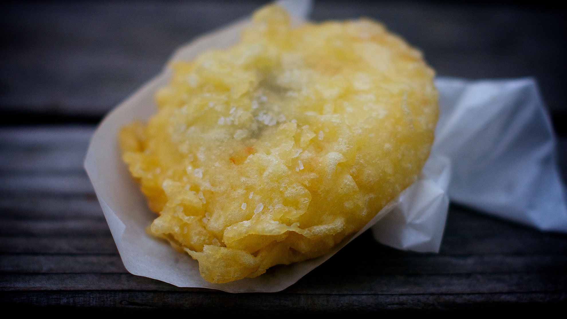 Crispy battered savoury pastry served on white greaseproof paper